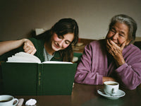 Una nonna ride mentre la nipote legge il libro delle sue memorie